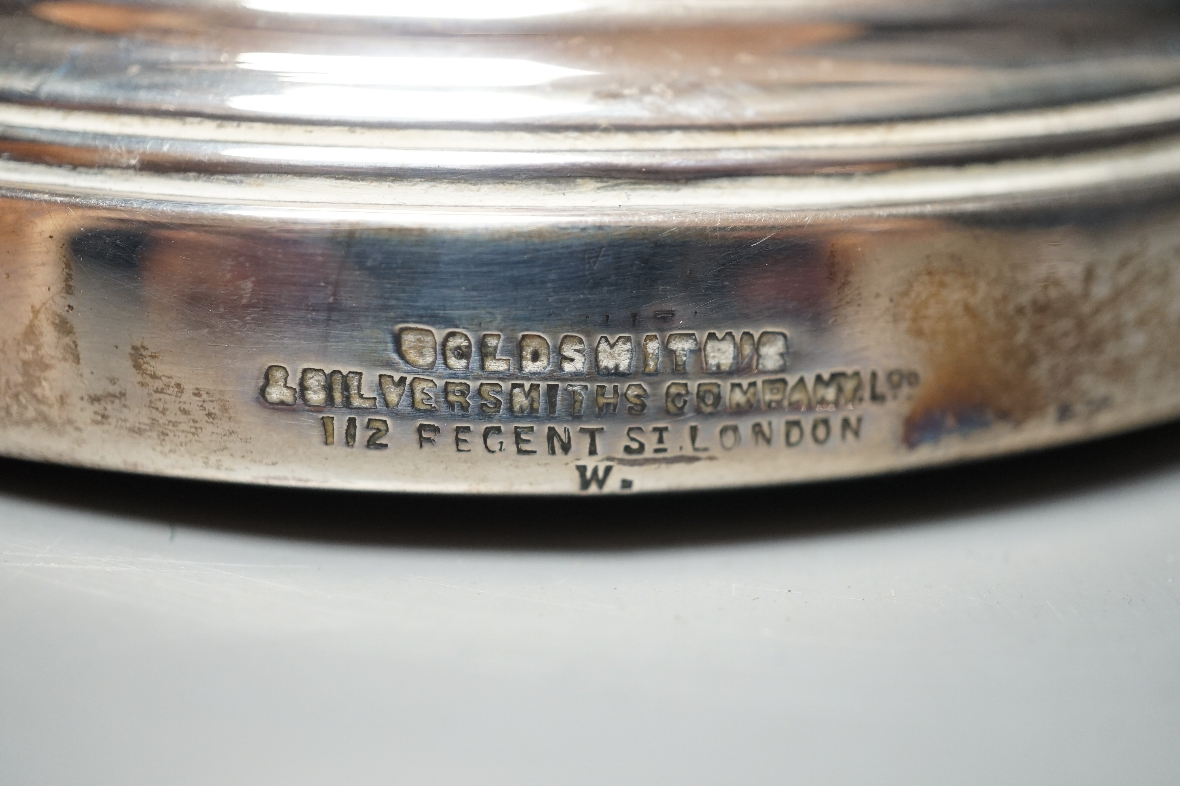 An Edwardian pierced silver mounted two handled syphon stand, by Goldsmiths & Silversmiths Co Ltd, London, 1903, 17.8cm, with turned wooden base.